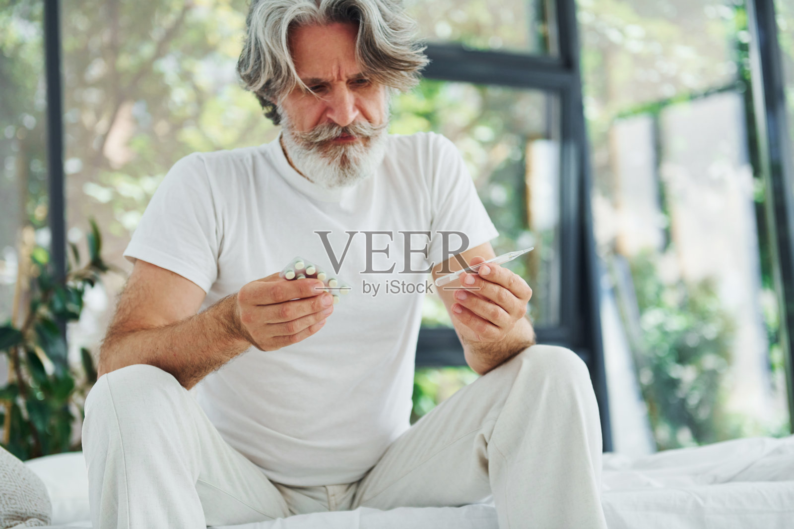 感觉病了。在床上。室内有灰色头发和胡子的高级时尚现代男士照片摄影图片