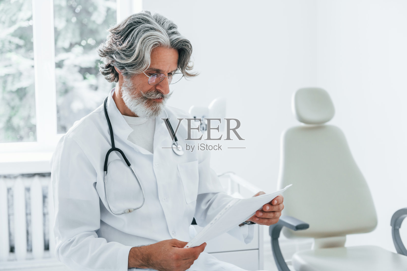 在诊所里，一名身穿白大褂、满头白发的资深男医生在室内照片摄影图片
