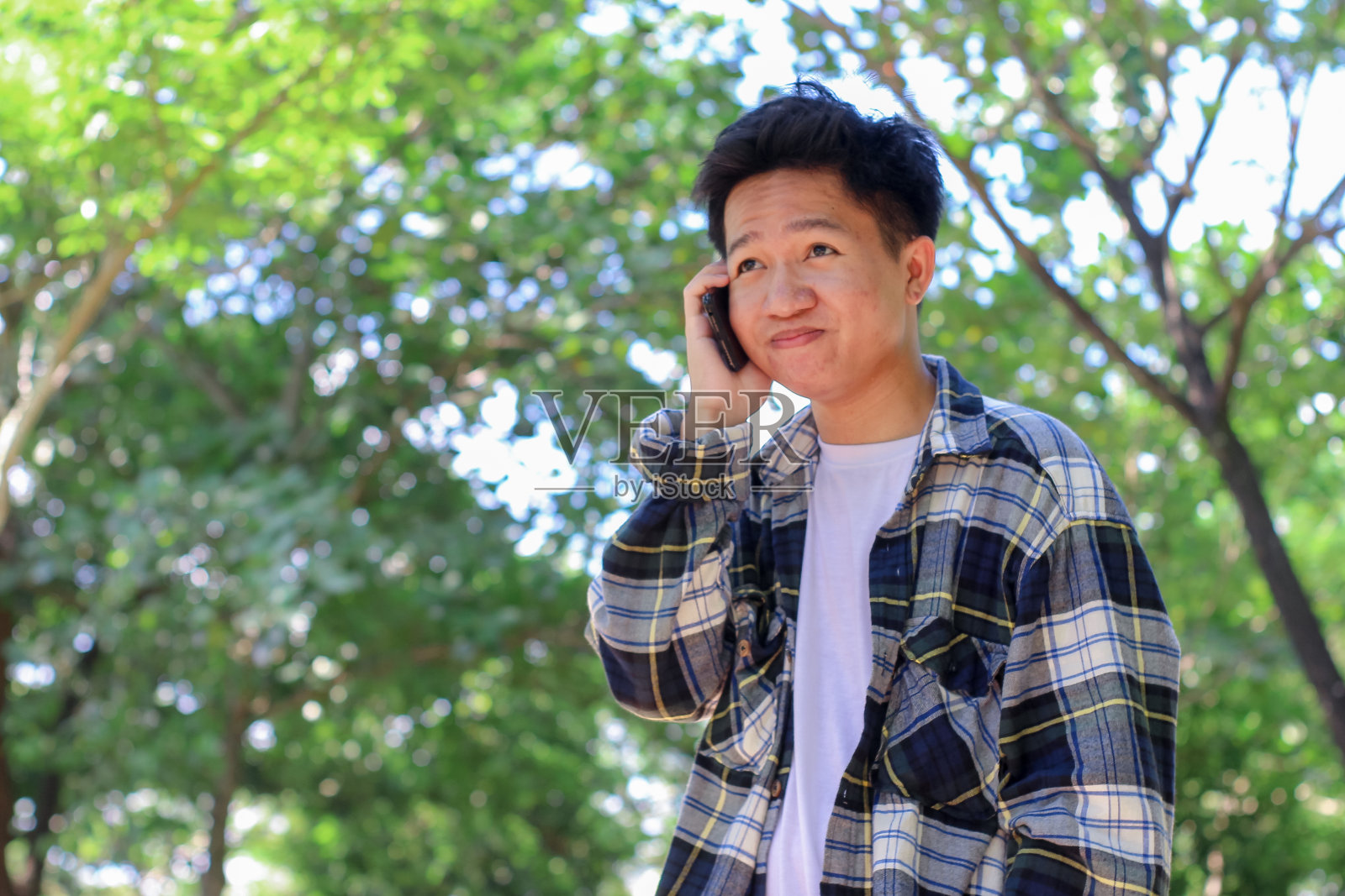 亚洲年轻人在公园里打电话照片摄影图片