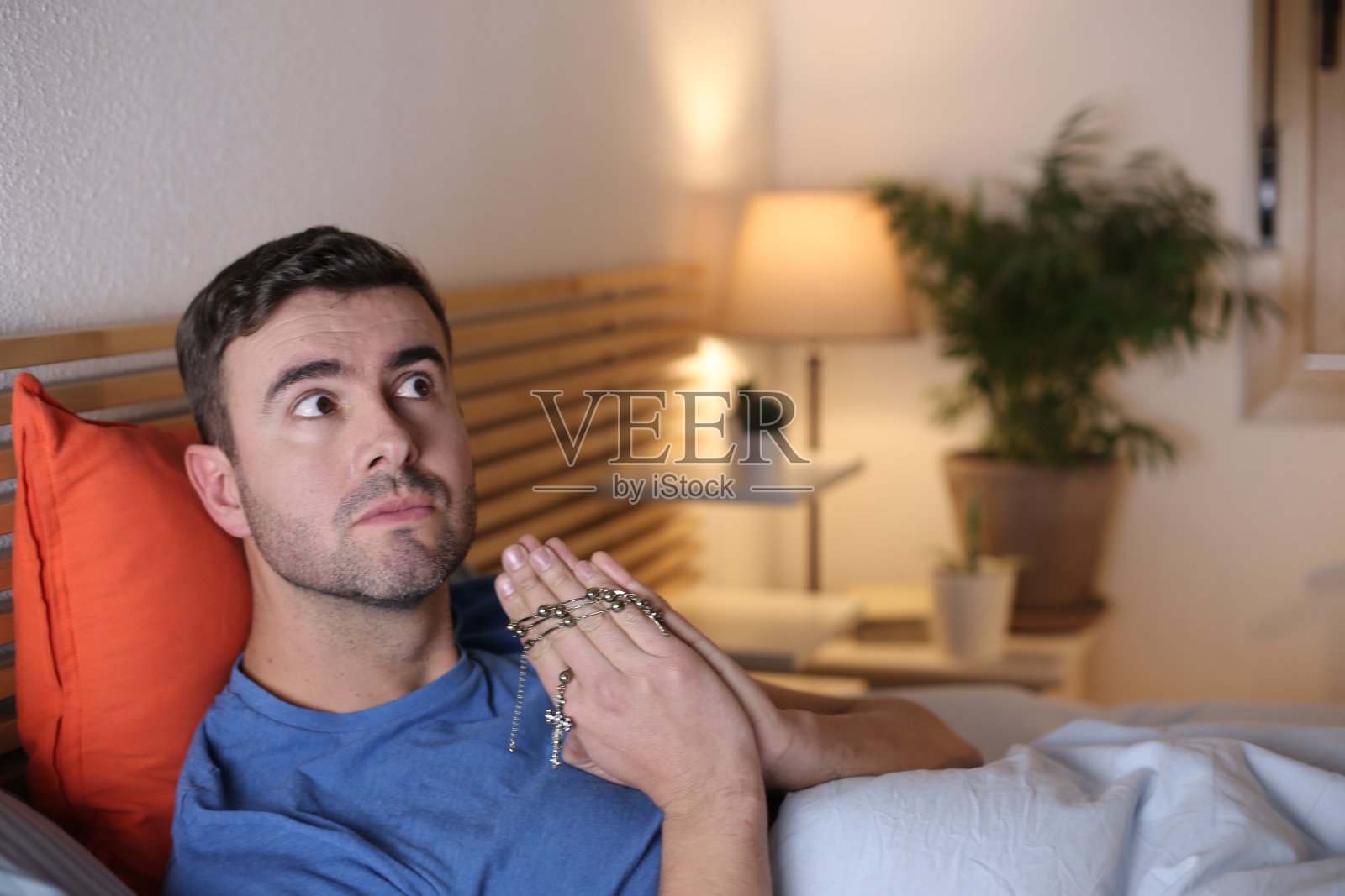 躺在床上祈祷的年轻人照片摄影图片