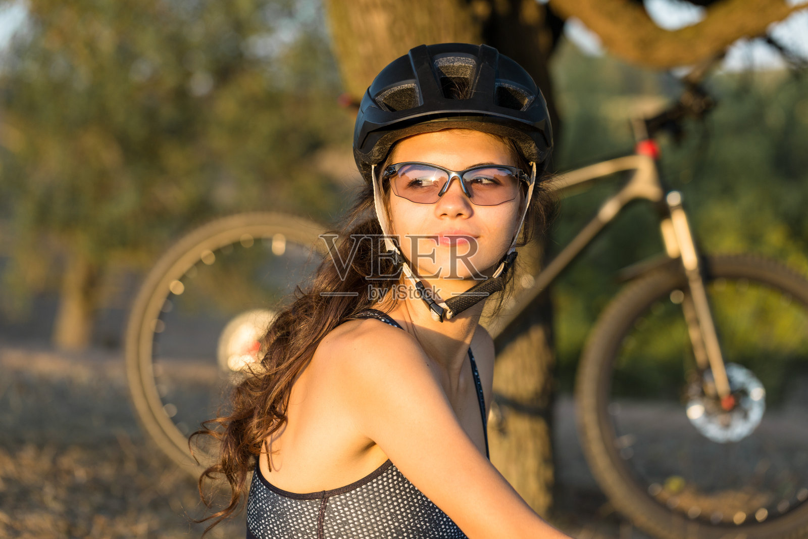 女孩在山地车越野，美丽的肖像自行车在日落，健身女孩骑现代碳纤维山地车。照片摄影图片