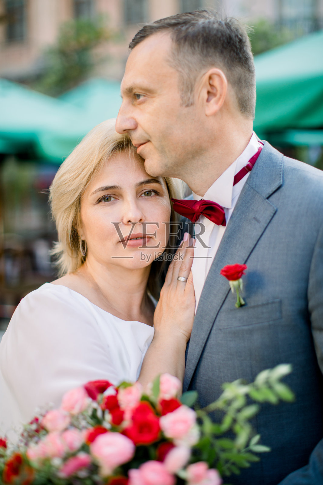 肉欲浪漫的老夫妇手持花束，在城市外彼此相依照片摄影图片