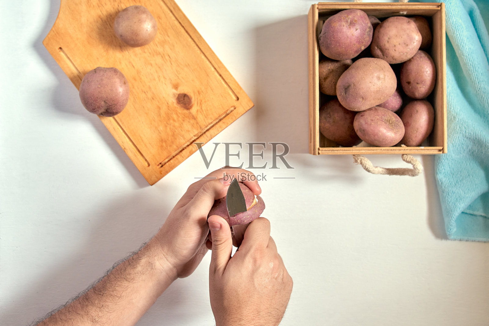 手在白色的桌子上削土豆照片摄影图片