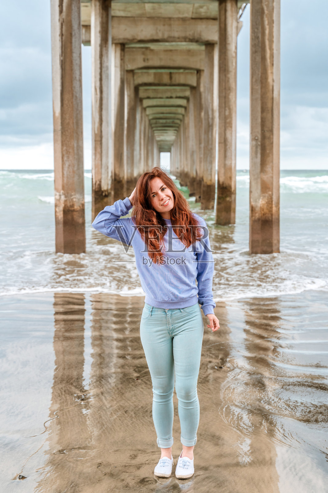 在多云的天气里，一位美丽的年轻女子站在拉霍亚码头下。加州圣地亚哥照片摄影图片