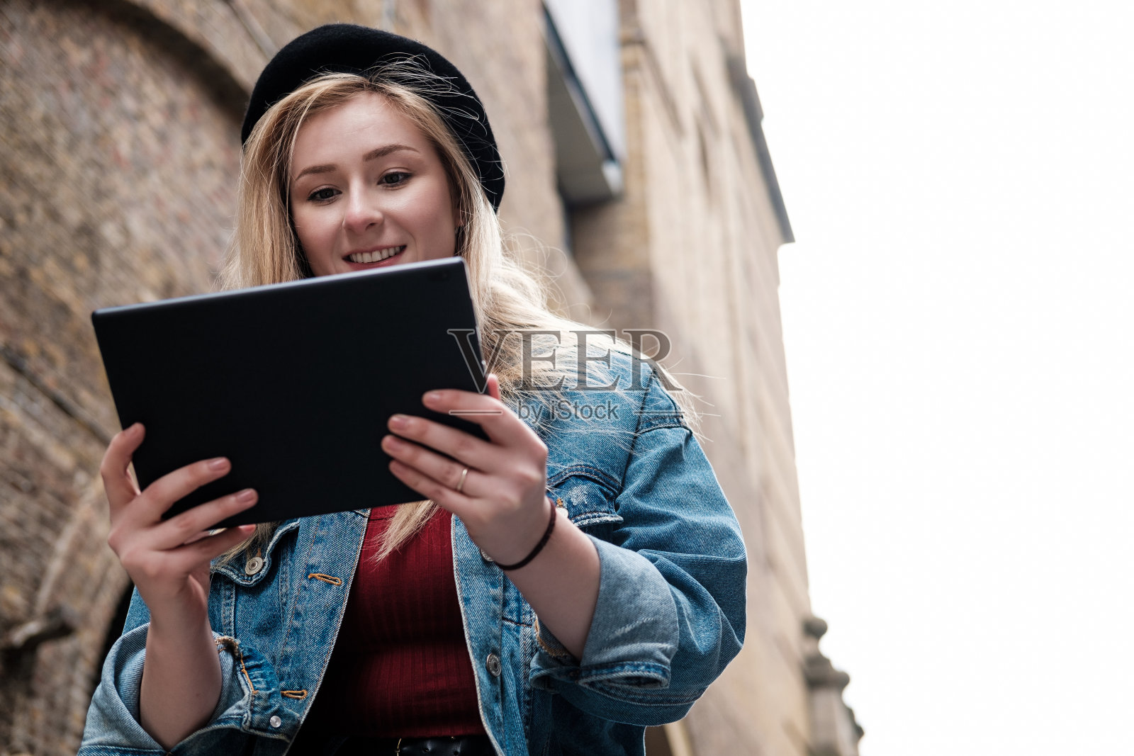 年轻女子在外面用平板电脑。照片摄影图片