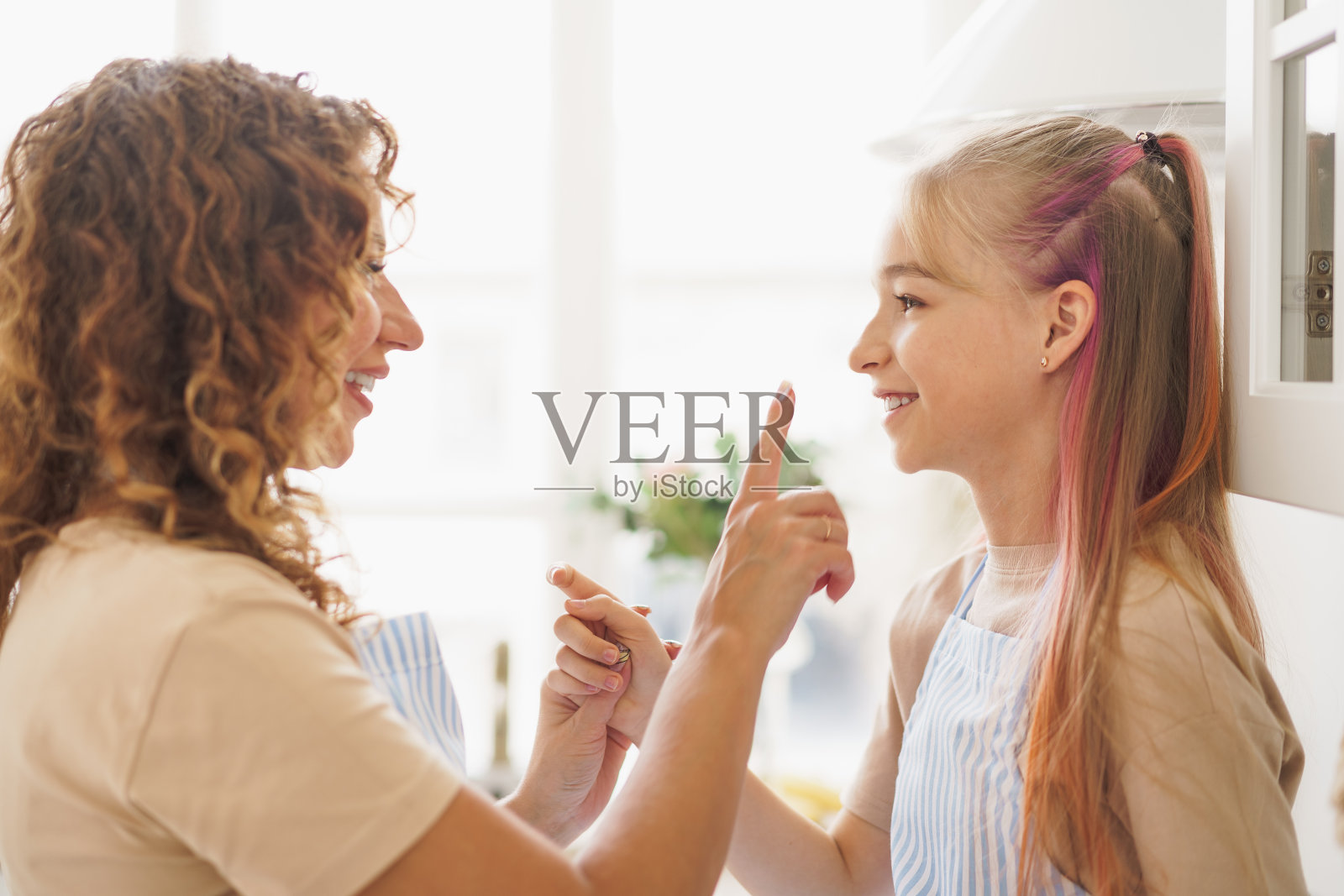 一个十几岁的女孩和她的母亲在家里的厨房里照片摄影图片