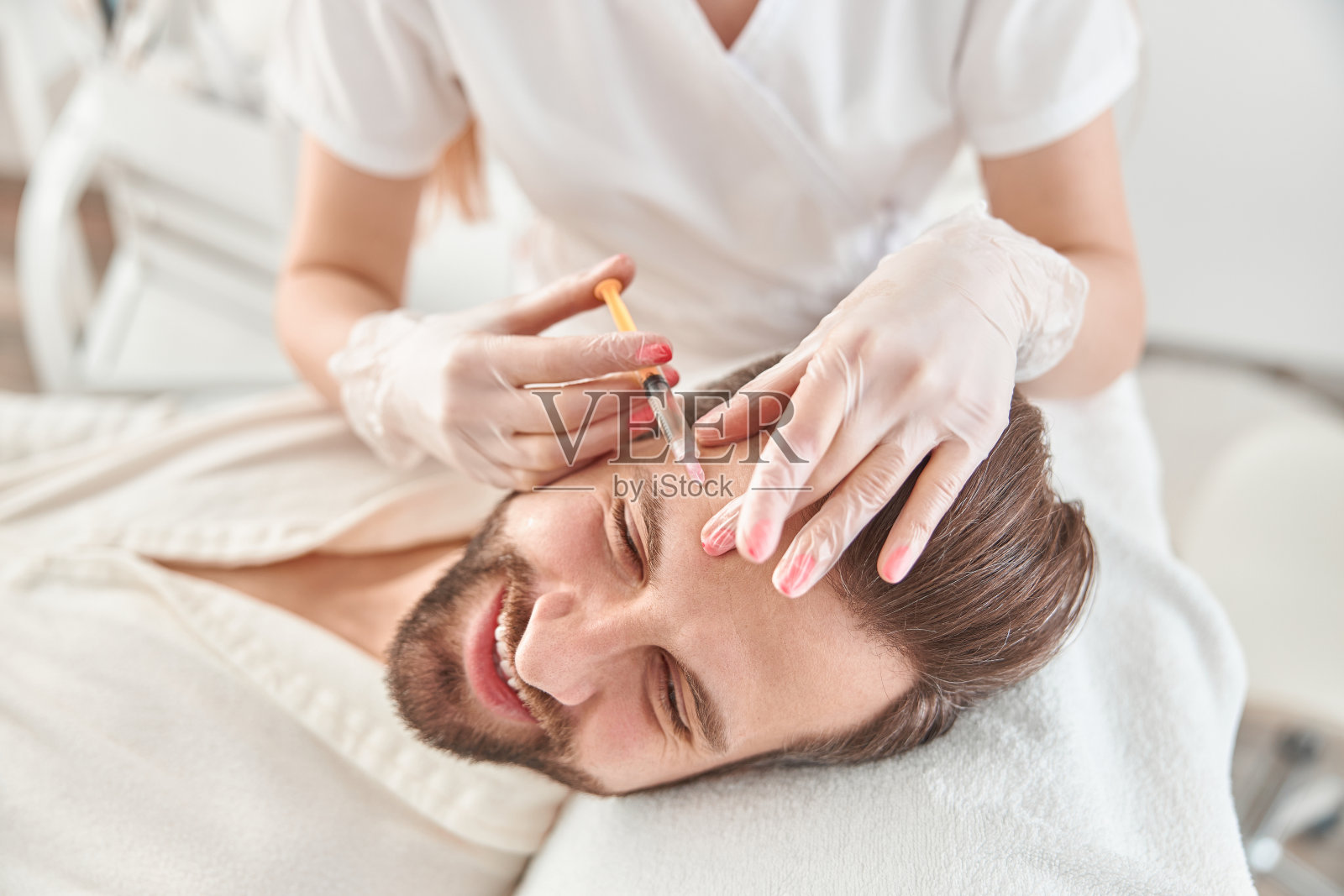 近距离给年轻人做中西医注射。由美容师为男性提供的面部皱纹紧致和平滑治疗照片摄影图片