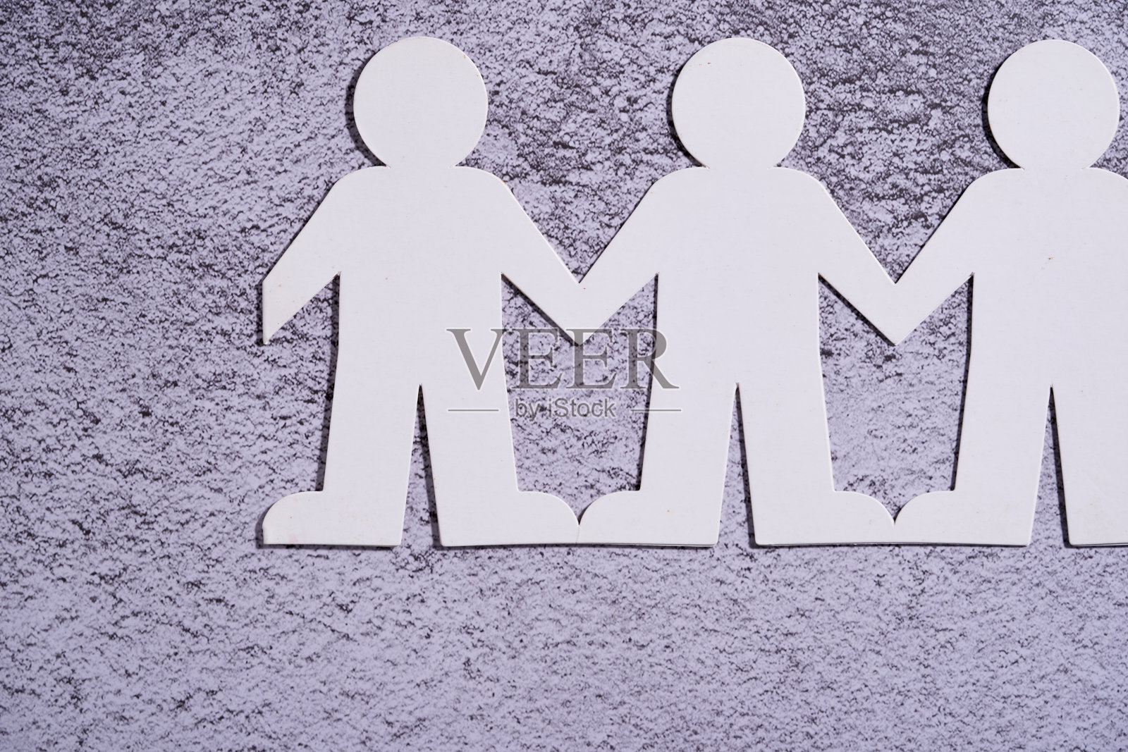 纸人链接在水泥背景上照片摄影图片