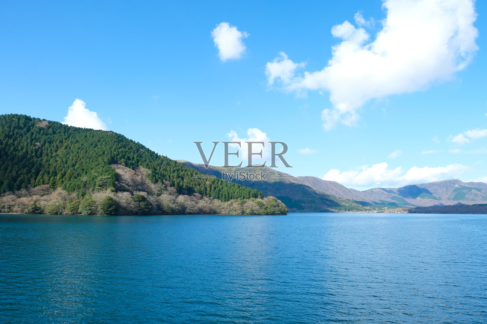 在阳光明媚的日子里，山脉覆盖着绿色的森林，蓝天背景，Ashi湖或箱根湖。照片摄影图片