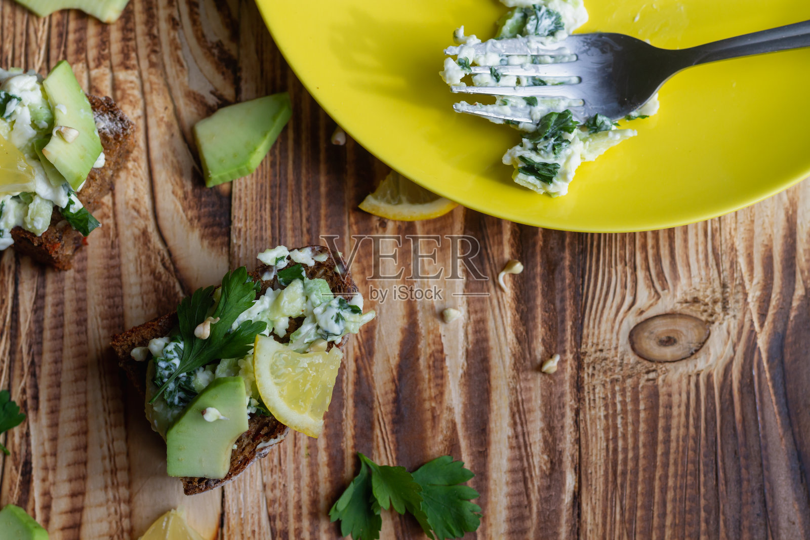 用叉子做牛油果酱三明治，配上发芽的绿色荞麦和柠檬黑麦面包照片摄影图片