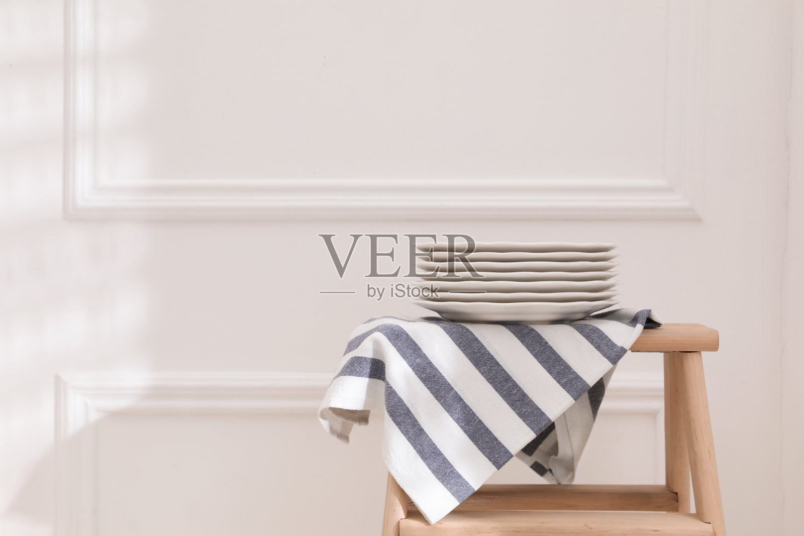 白墙旁边的木架上放着毛巾和干净的餐具。空间的文本照片摄影图片