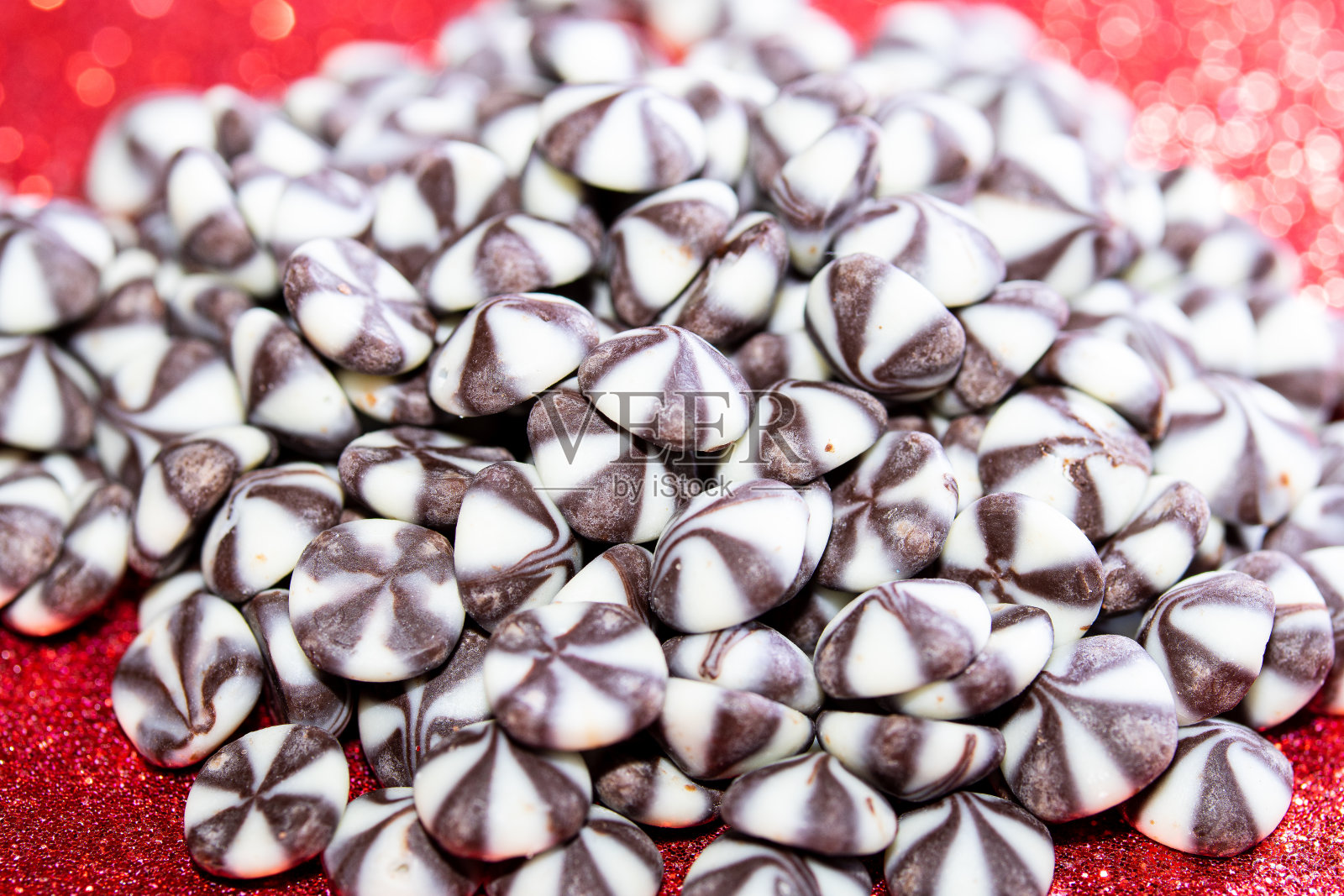 两颗彩色巧克力，红色背景和散景照片摄影图片