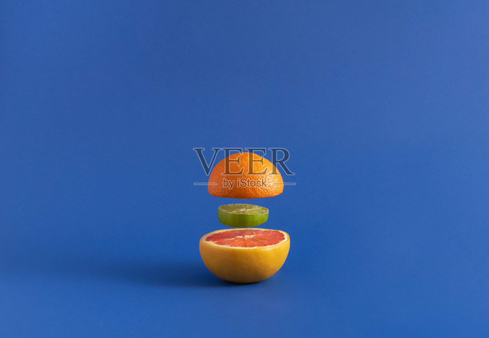 在海军蓝的背景上切成汉堡包形状的柑橘类水果，象征着一种健康的食物照片摄影图片