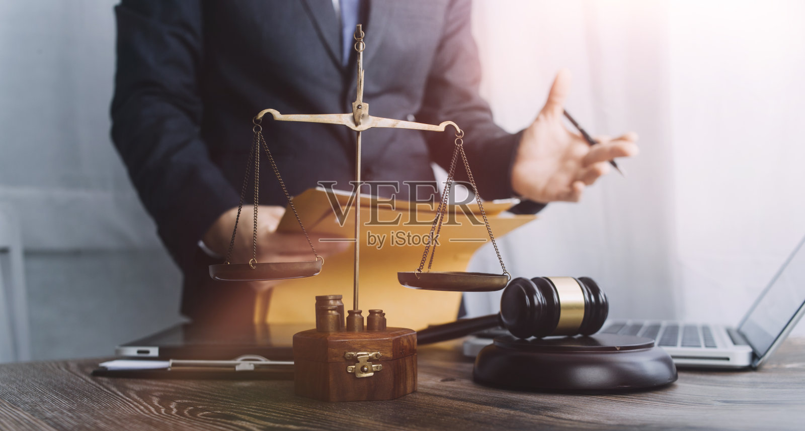 正义与法律观念。男法官在法庭上拿着木槌，工作，电脑和对接键盘，眼镜，在晨光下放在桌子上照片摄影图片