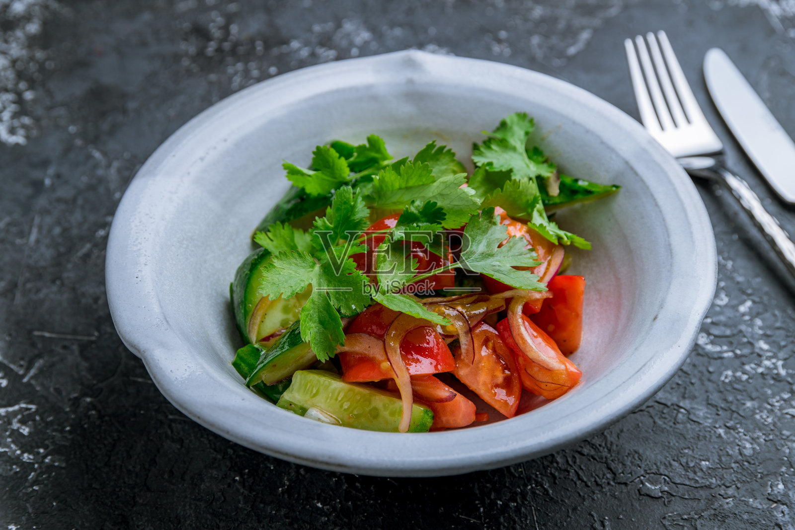 在黑色的石头桌上，有西红柿、黄瓜和洋葱的蔬菜沙拉照片摄影图片