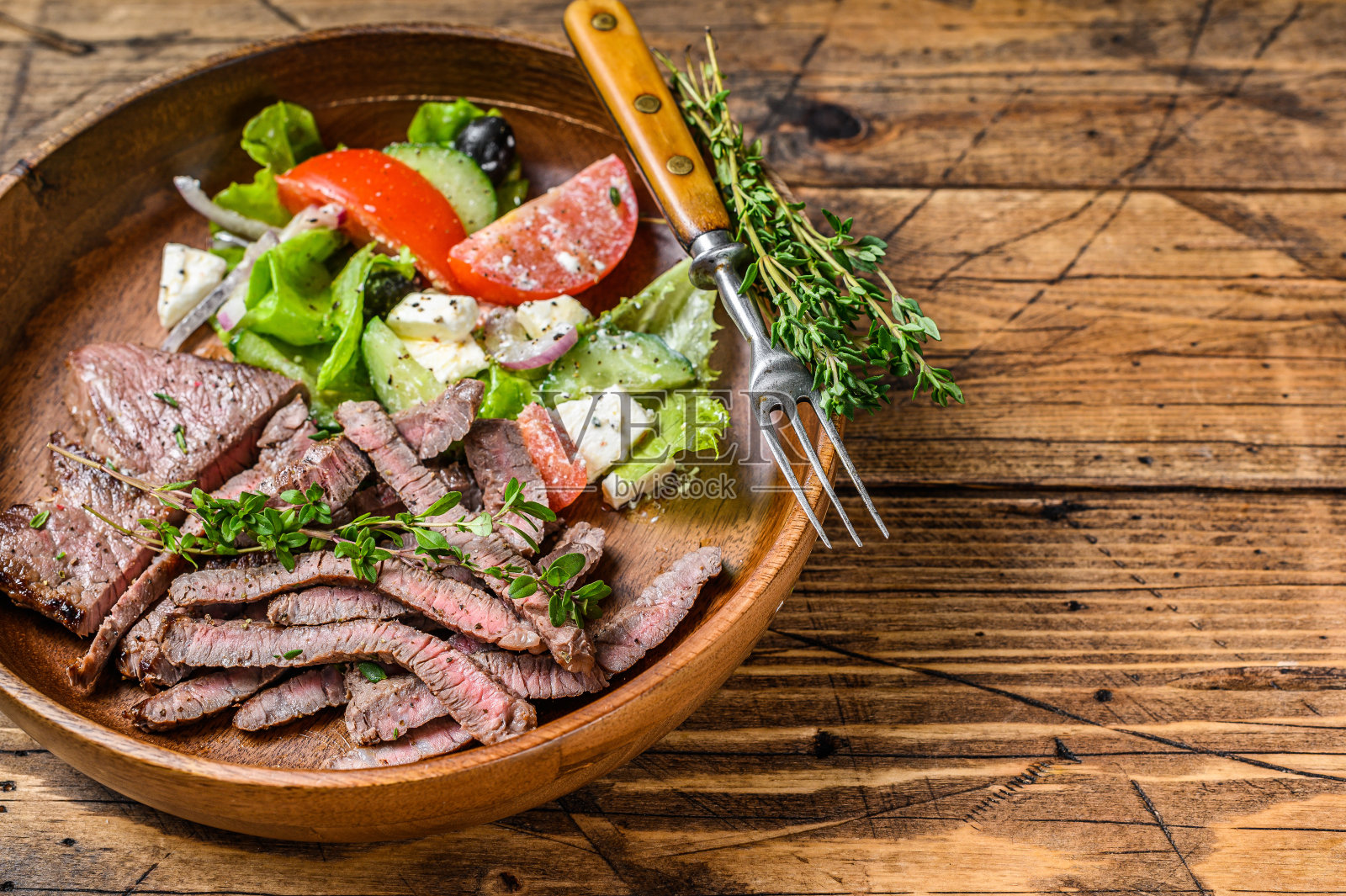 烧烤用的木盘上的牛肉排和蔬菜沙拉。木制背景。前视图。本空间照片摄影图片