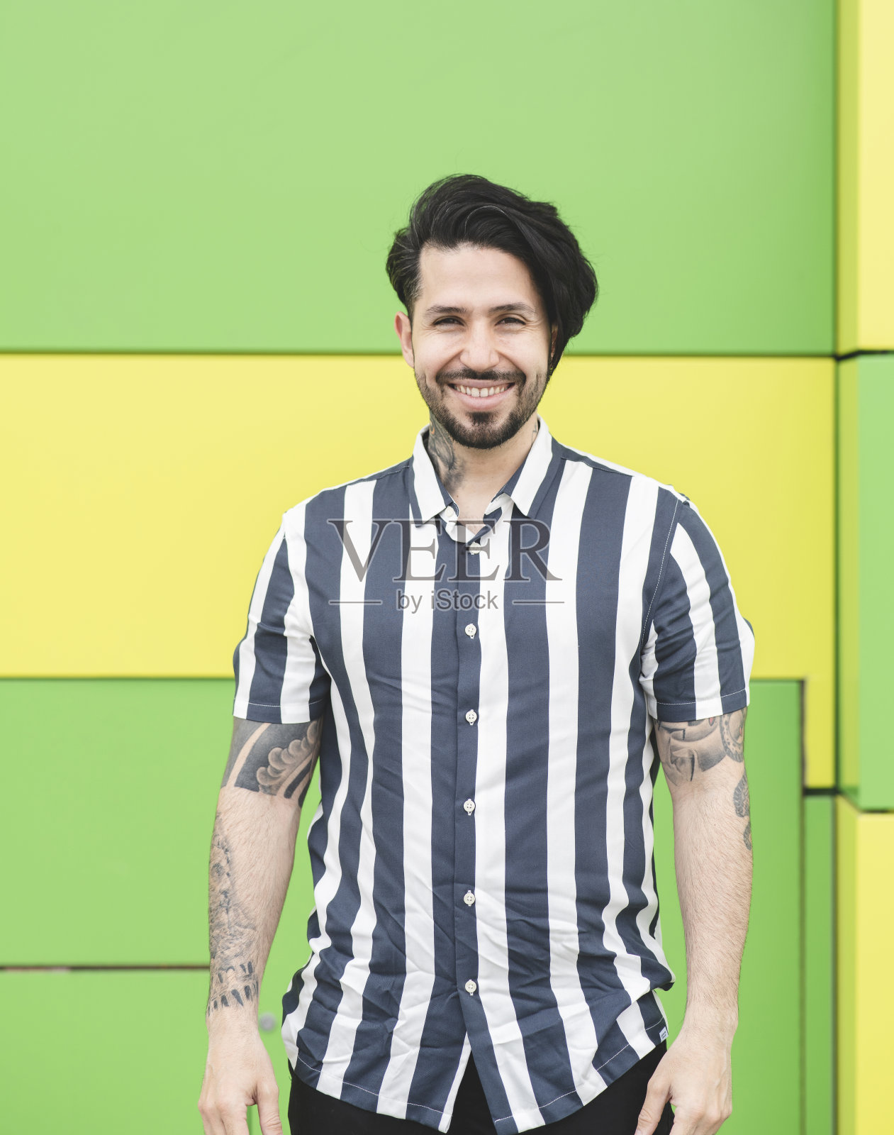 身着条纹衬衫的绿色背景男子，面带微笑照片摄影图片