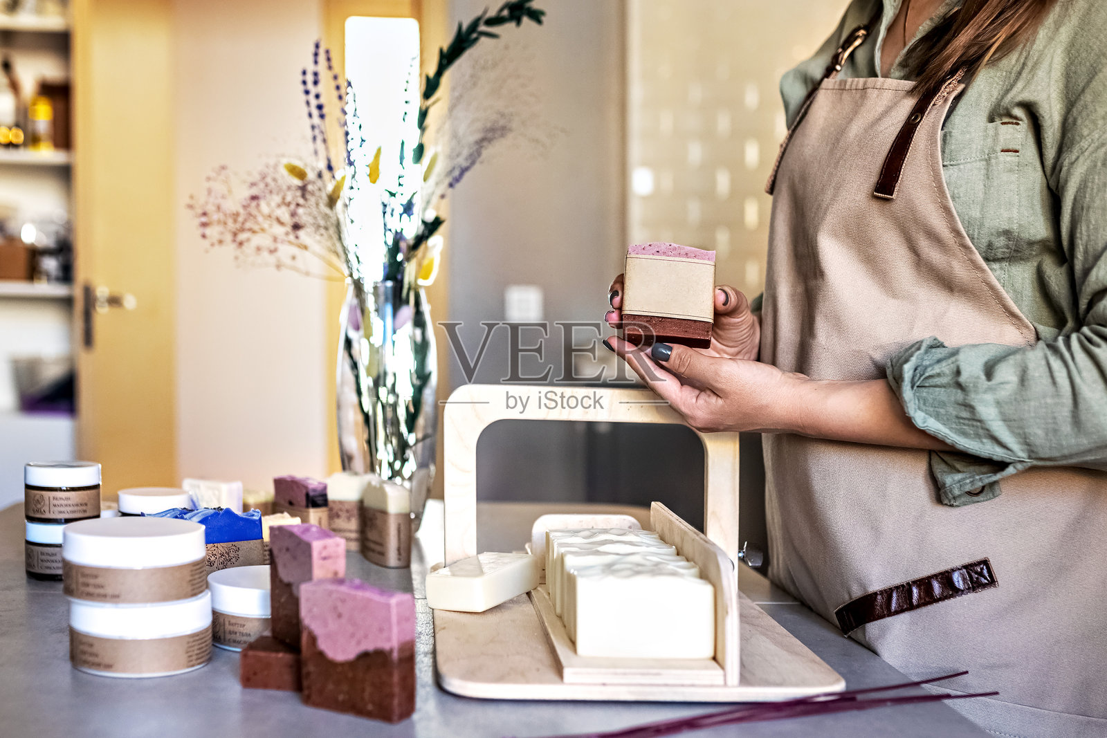 一个做肥皂的女孩手里拿着一块刚煮好的手工肥皂。烹饪过程。家庭spa。小生意。照片摄影图片