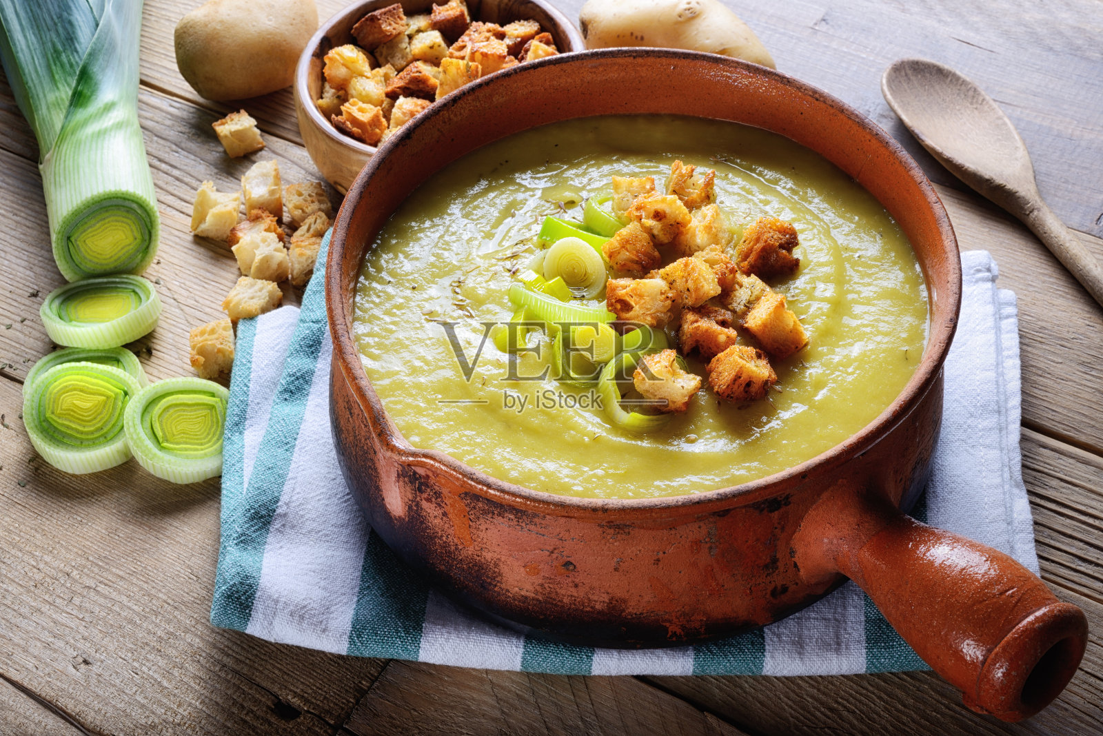 乡村木桌上的韭菜土豆汤配烤面包丁，特写镜头。照片摄影图片