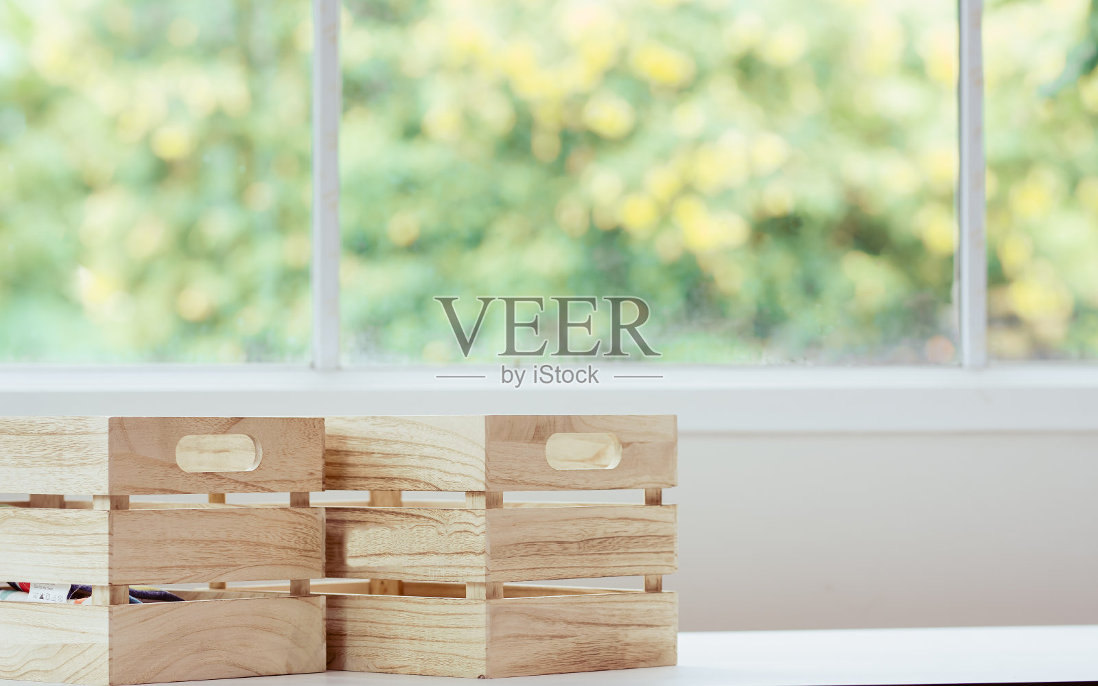 在室内舒适的家中厨房窗边的桌子上放两个木箱或盒子背景和复制空间，模糊了室外的树木自然和日光。照片摄影图片