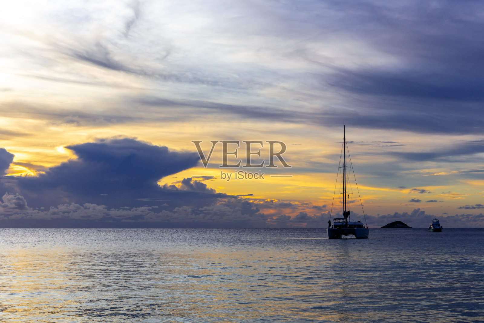 戏剧性的日落与风暴云在地平线上，游艇的剪影，安塞拉齐奥，塞舌尔。照片摄影图片