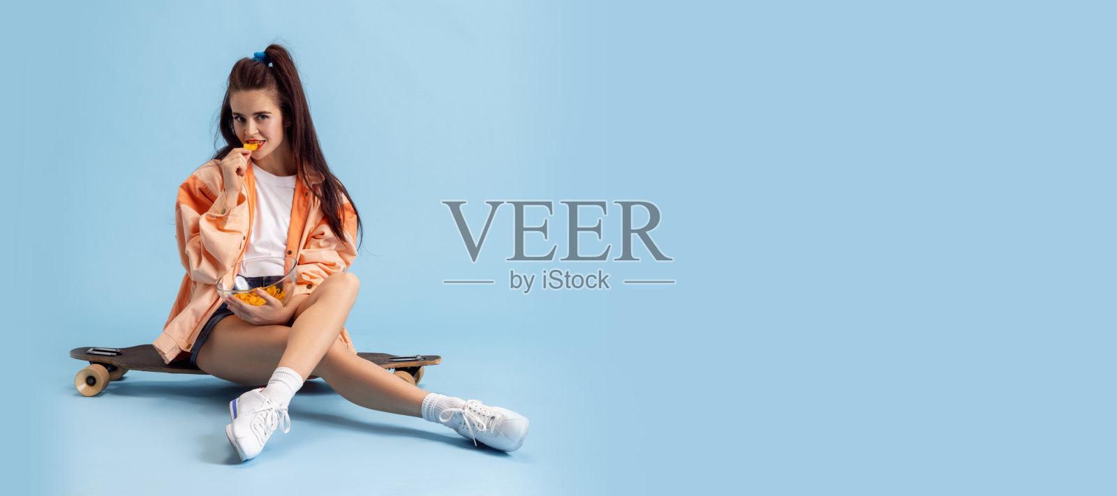 美丽可爱的年轻女孩在复古的90年代时尚风格，在粉红色的工作室背景上滑板孤立的服装。美丽、时尚、青春的概念。摩天观景轮照片摄影图片