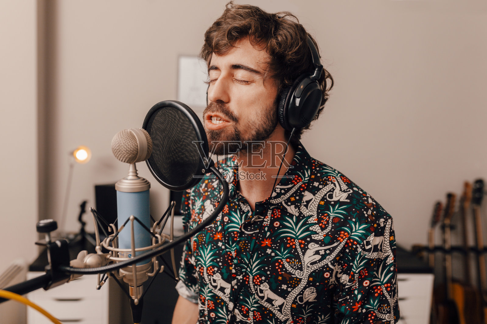 千禧一代男歌手戴着耳机在录音棚里唱歌照片摄影图片