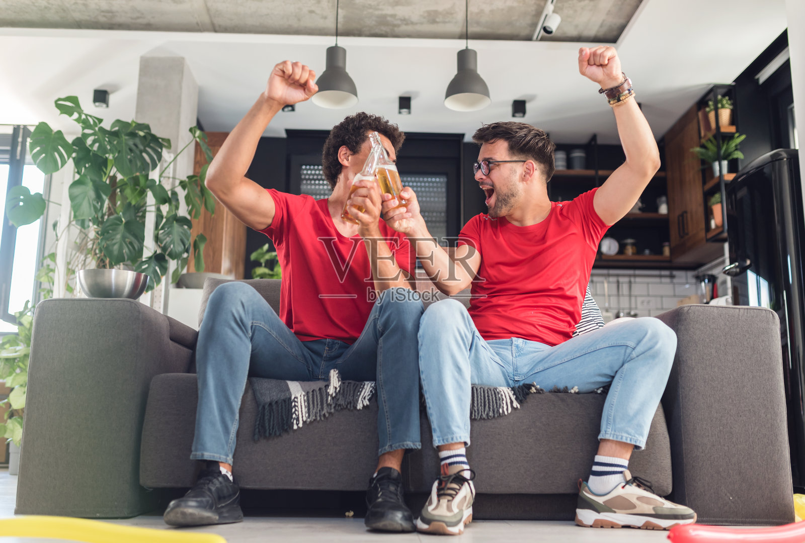 几个朋友在玩，在电视上看比赛。为他们的运动队欢呼照片摄影图片