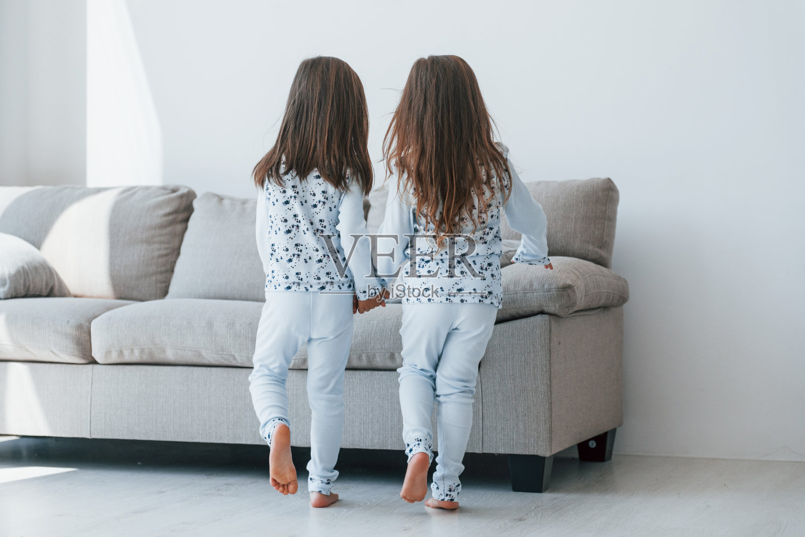 牵着对方的手。两个可爱的小女孩一起呆在家里。孩子们玩得开心照片摄影图片