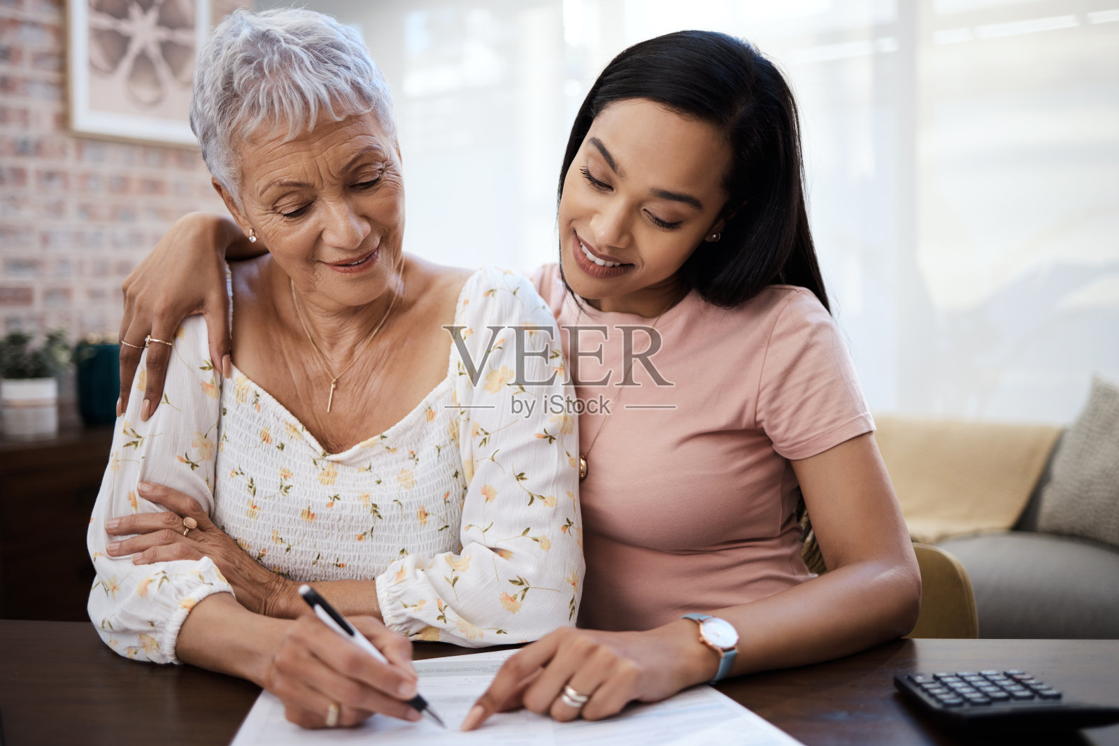 一个年轻女人在家里和她年迈的母亲一起检查文件照片摄影图片