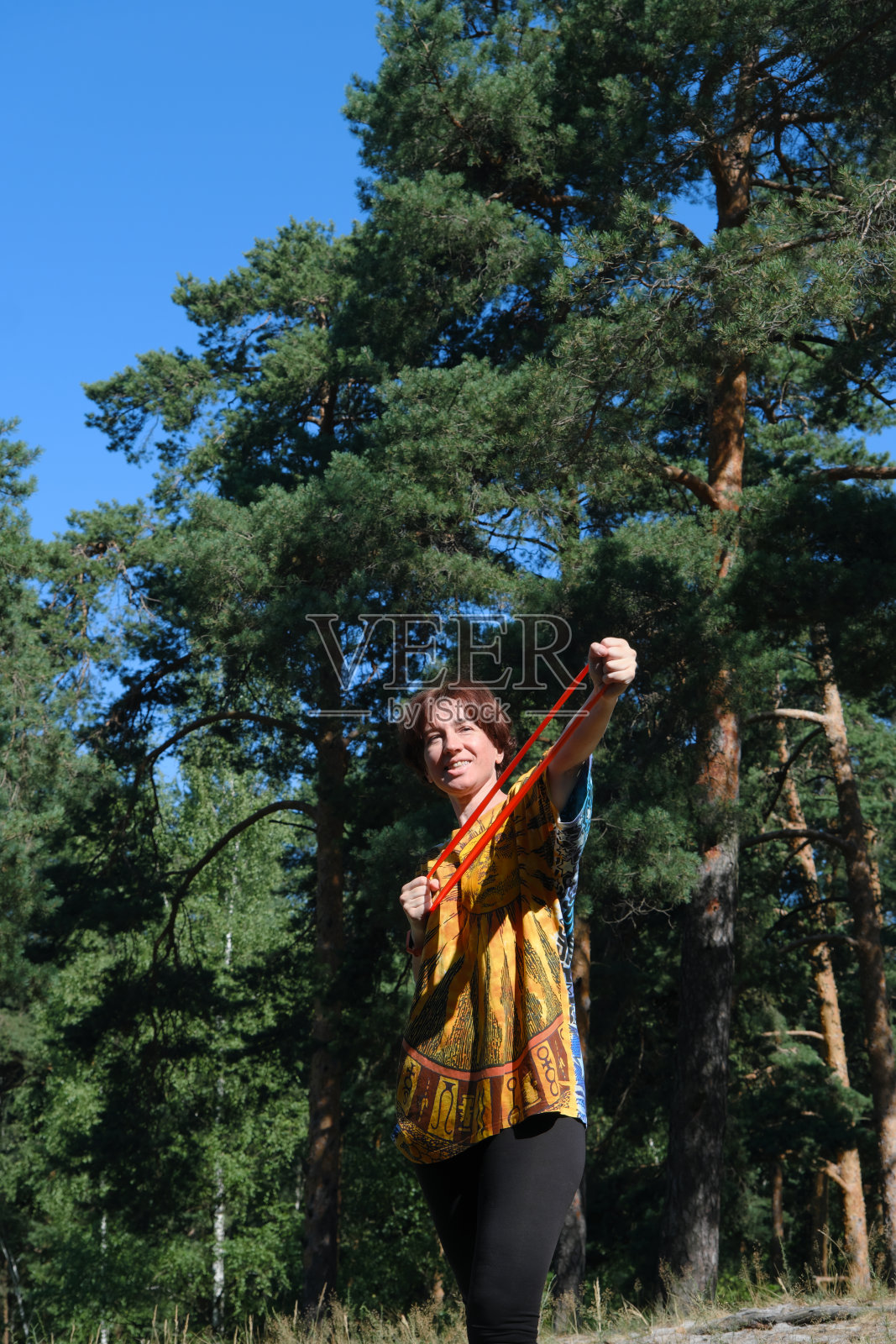 成熟的女人在自然公园用抵抗带锻炼照片摄影图片