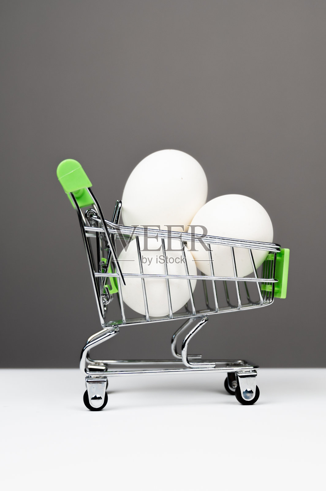 灰色背景下，购物车里放着新鲜的白鸡蛋照片摄影图片