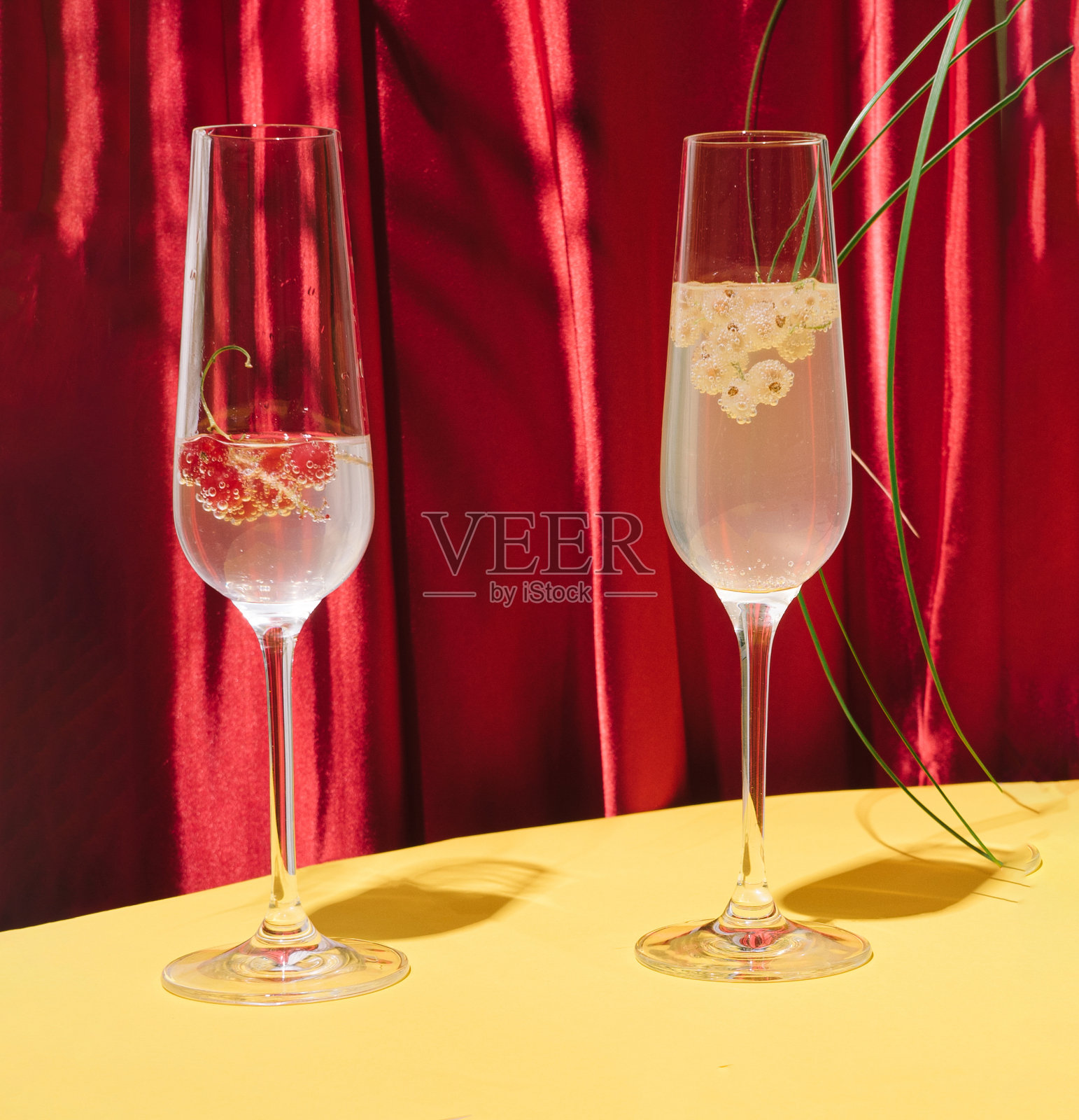 时尚的红色丝质底色，暖黄色底色。两杯红醋栗和黄醋栗的鸡尾酒。照片摄影图片