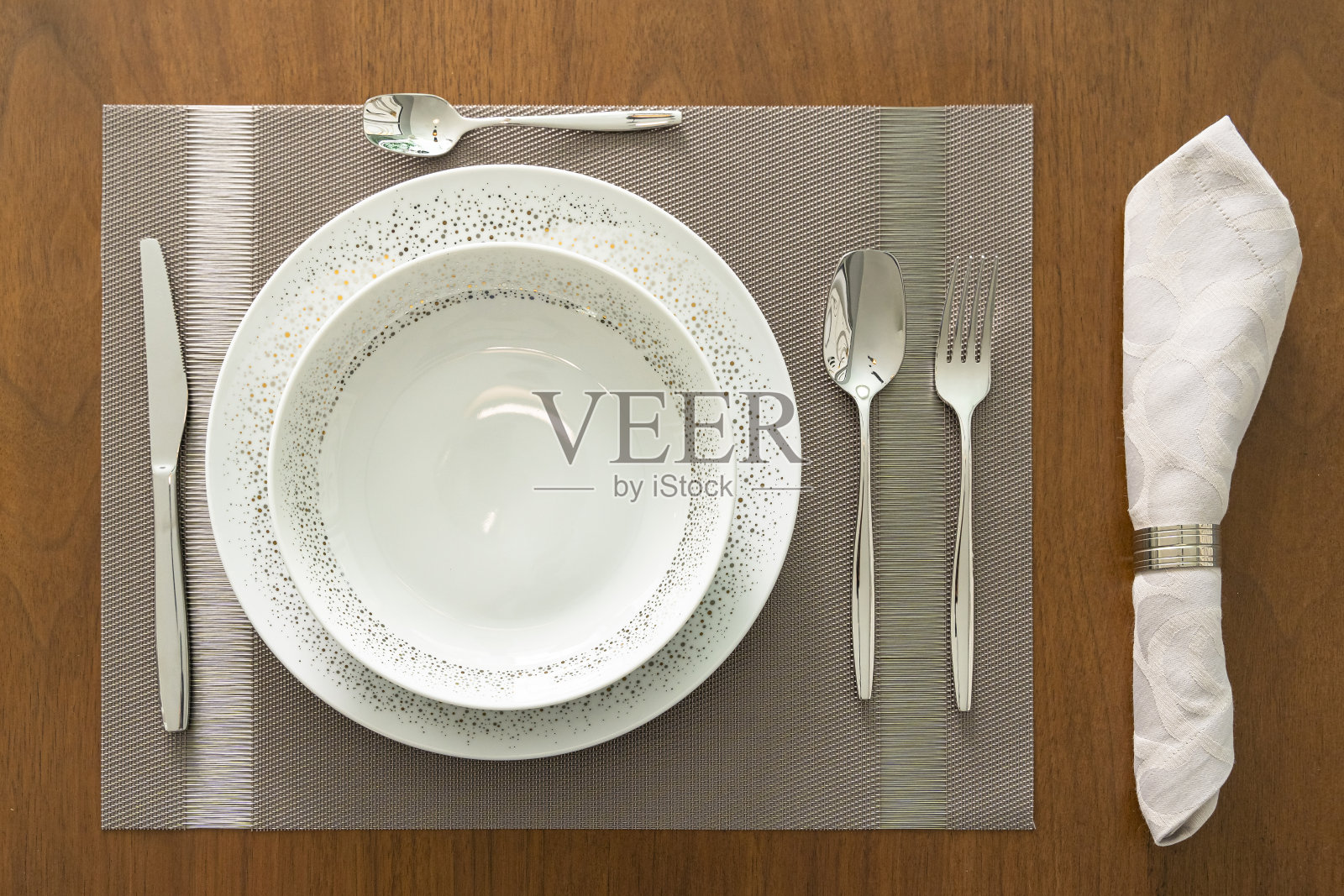 家庭餐桌设置，白色盘子，银叉勺刀和餐巾，俯视图，餐厅木桌照片摄影图片