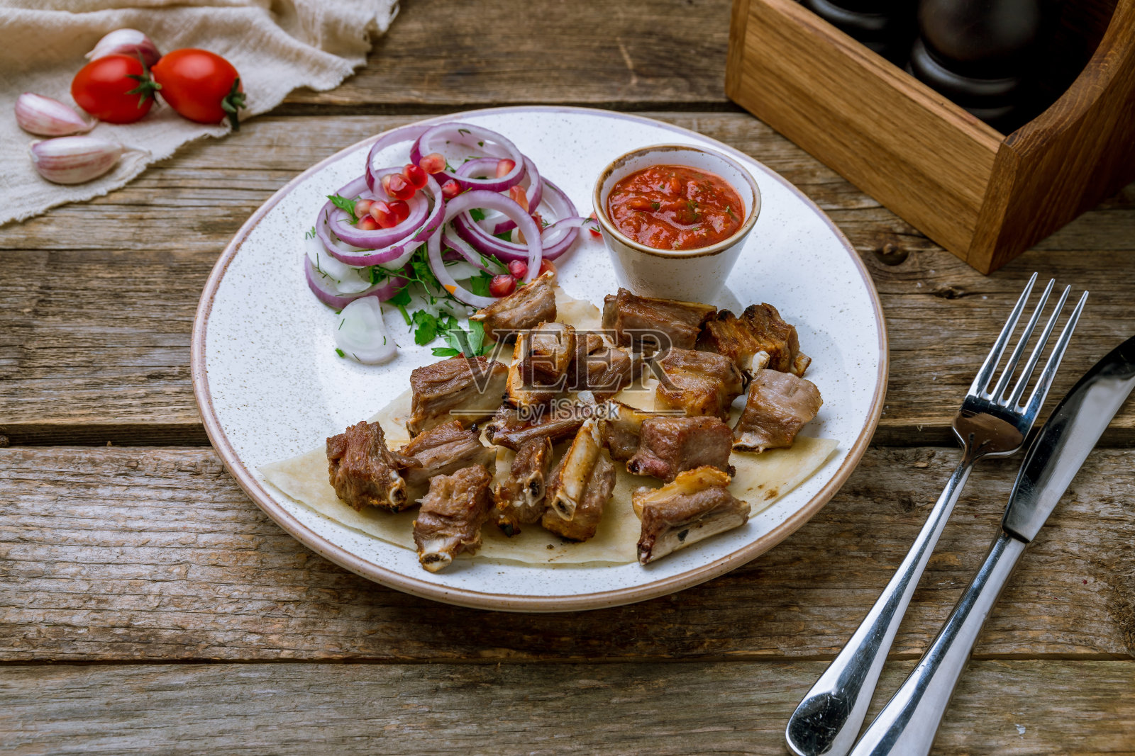 旧木桌上的烤羊排配红洋葱、石榴子和番茄酱照片摄影图片