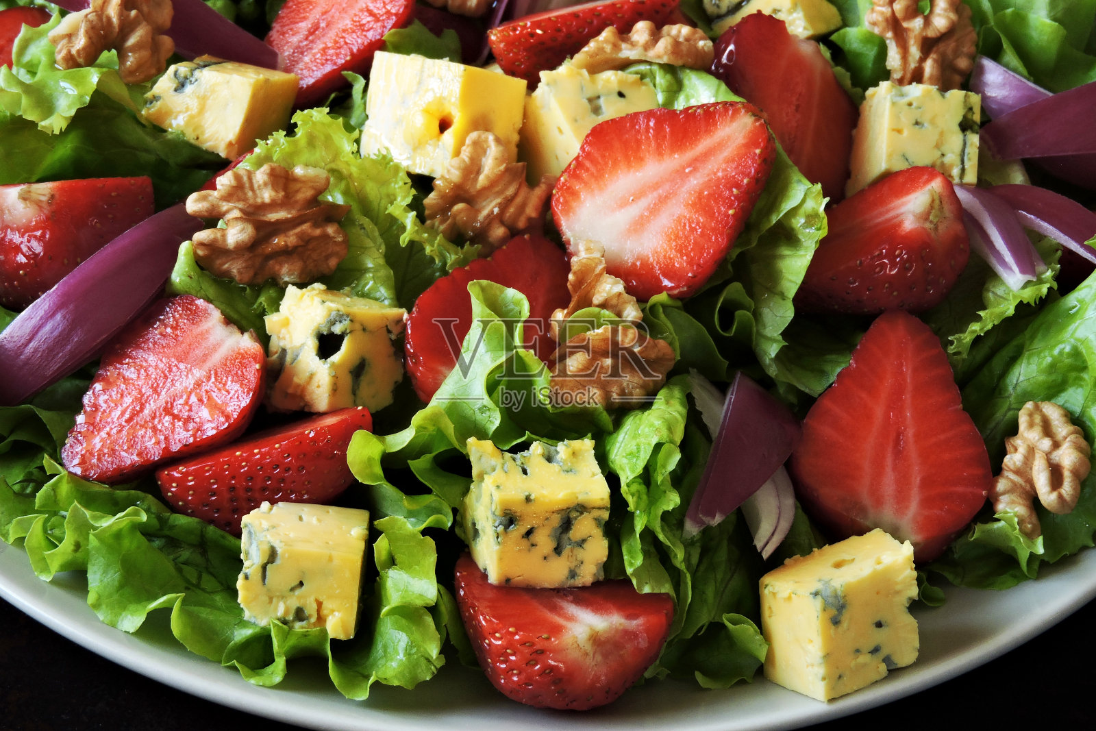 配有草莓和奶酪的健康沙拉盘。照片摄影图片