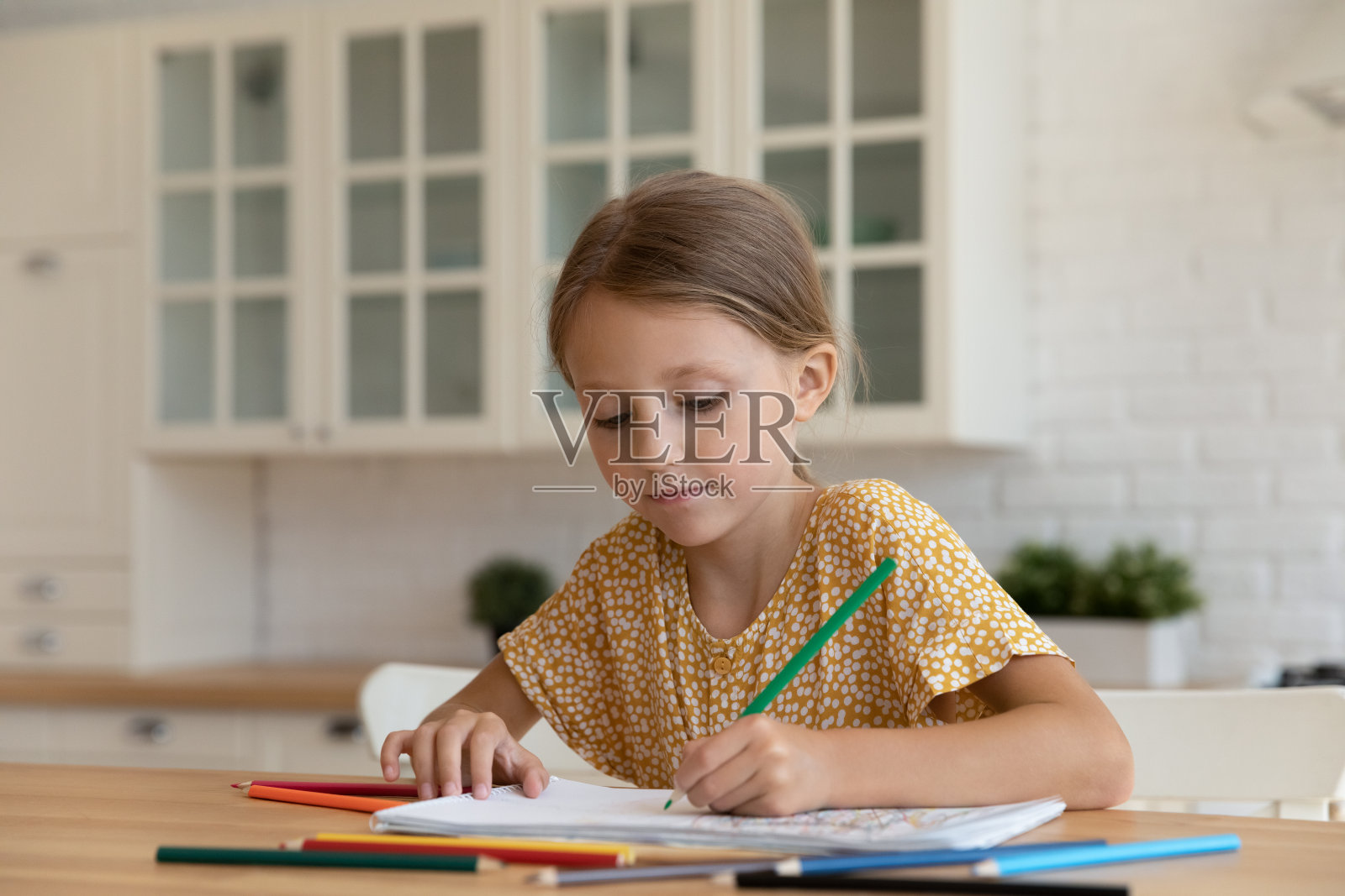 专心漂亮的小女孩在画册里画画。照片摄影图片