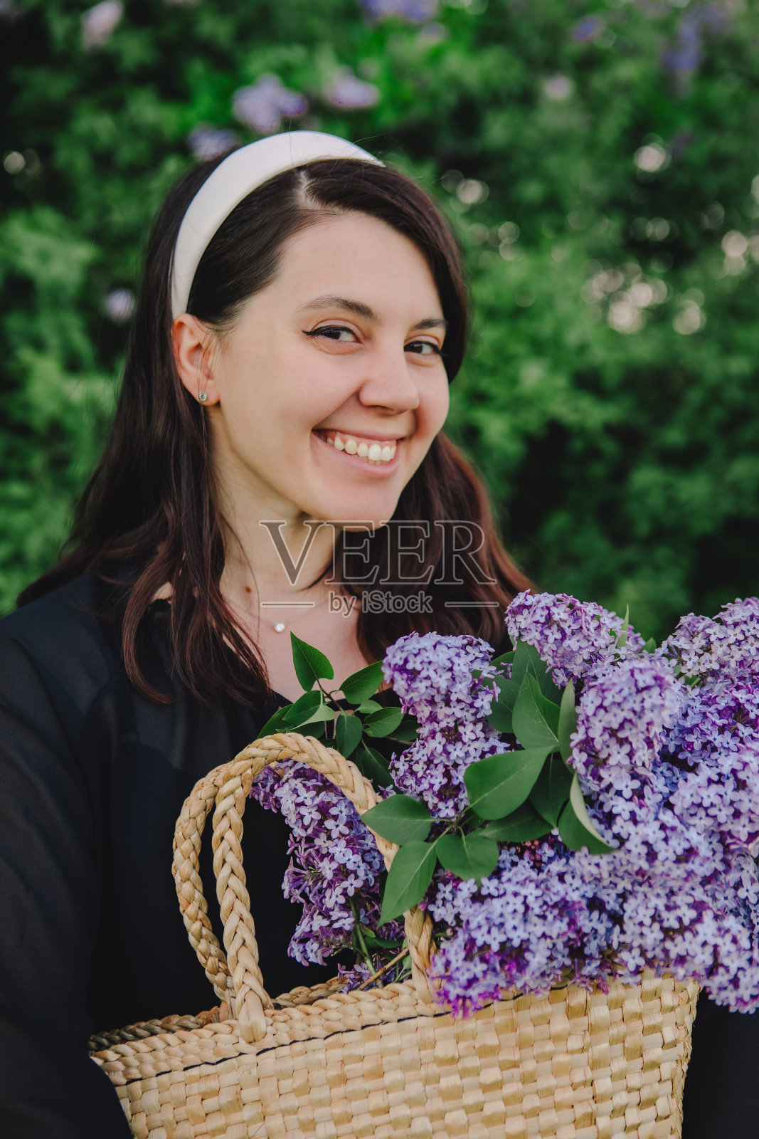 美丽的女人拿着淡紫色的花摆姿势照片摄影图片