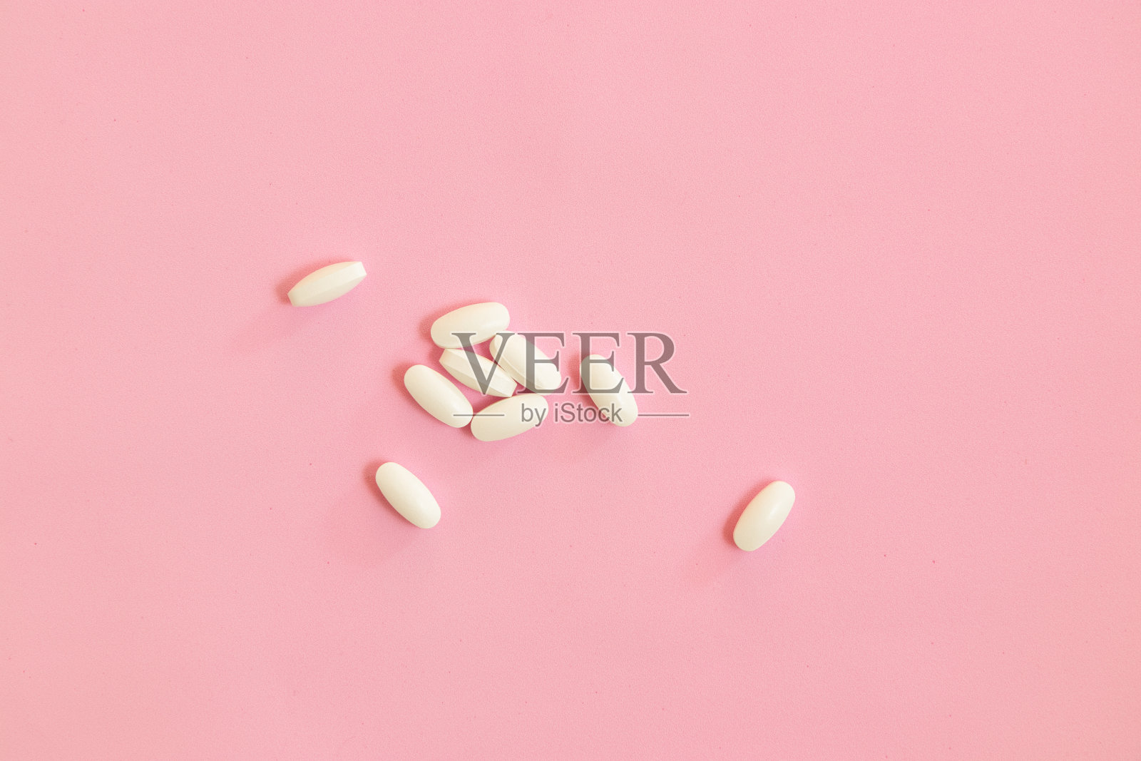 白色药丸，粉色背景上的止痛药。照片摄影图片