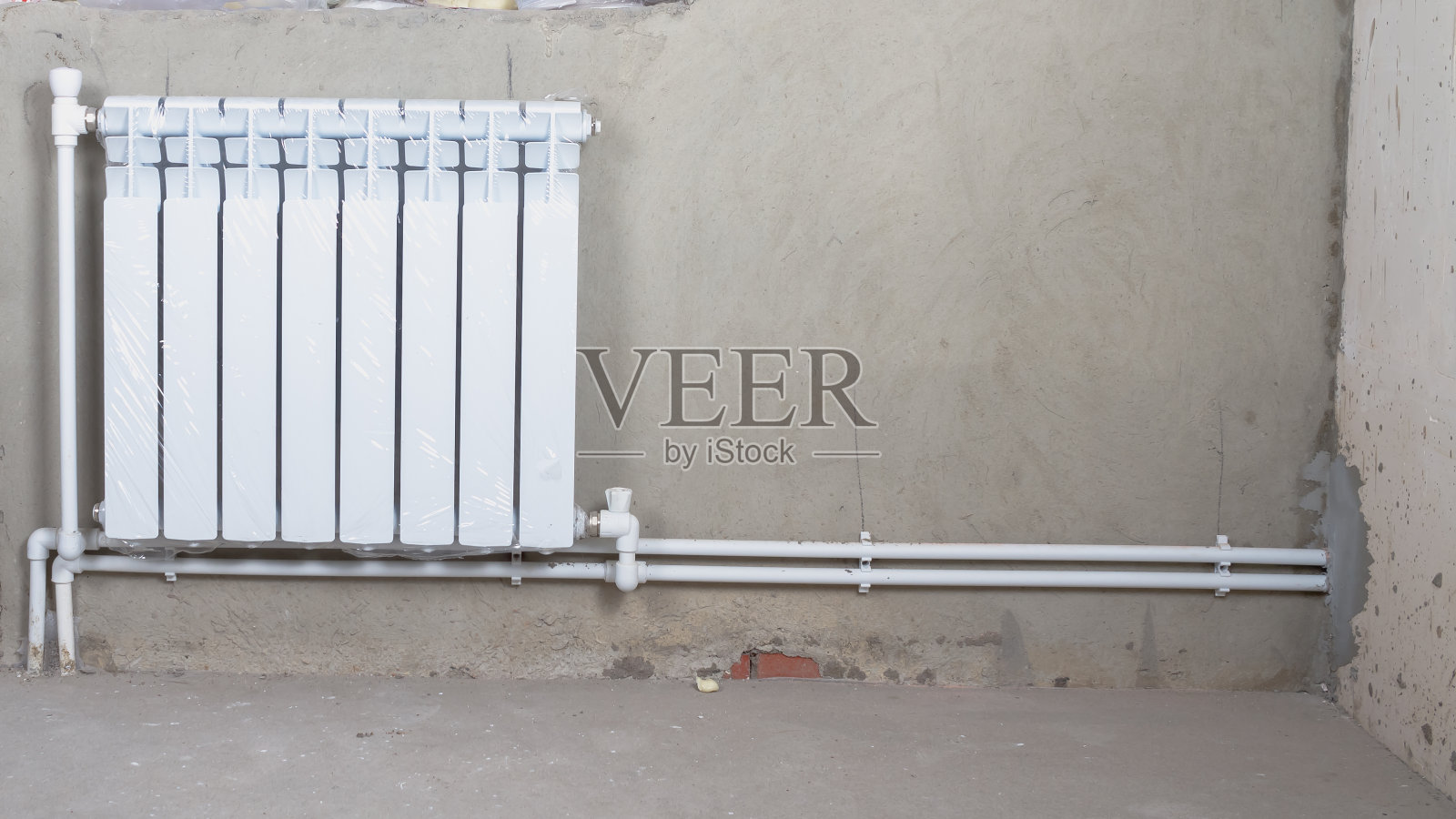 在水泥墙背景的新房子里的一个新的加热电池照片摄影图片