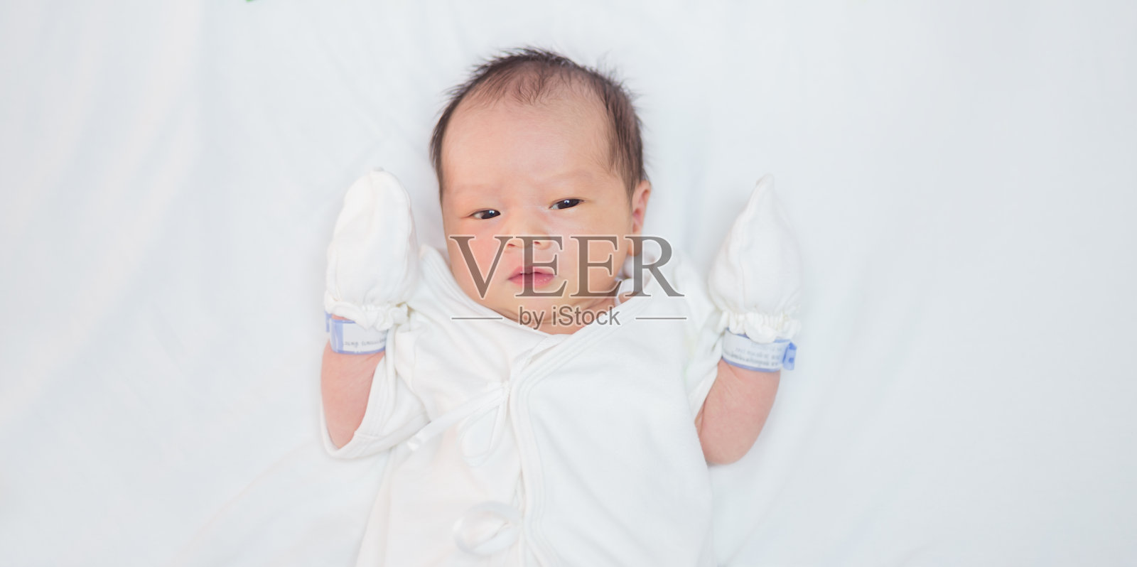 亚洲婴儿的特写肖像睡在白色的床与复制空间，家庭爱新生儿医院保健托儿所的概念。照片摄影图片