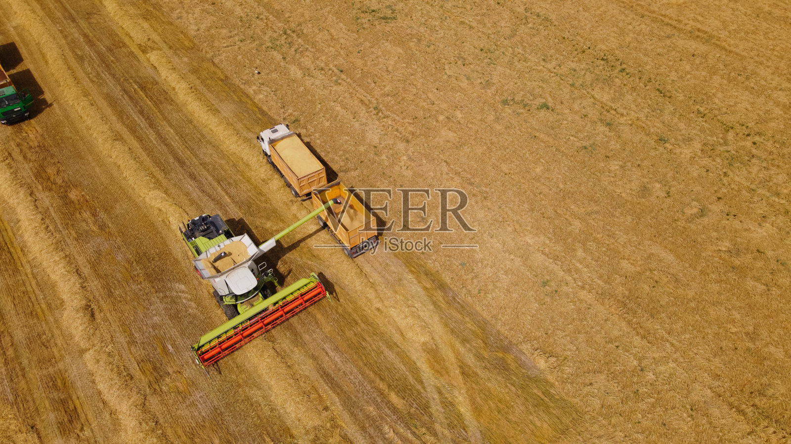 田间联合收割机。谷物收获。把谷物从联合收割机的仓里转移到卡车上。航空摄影。照片摄影图片