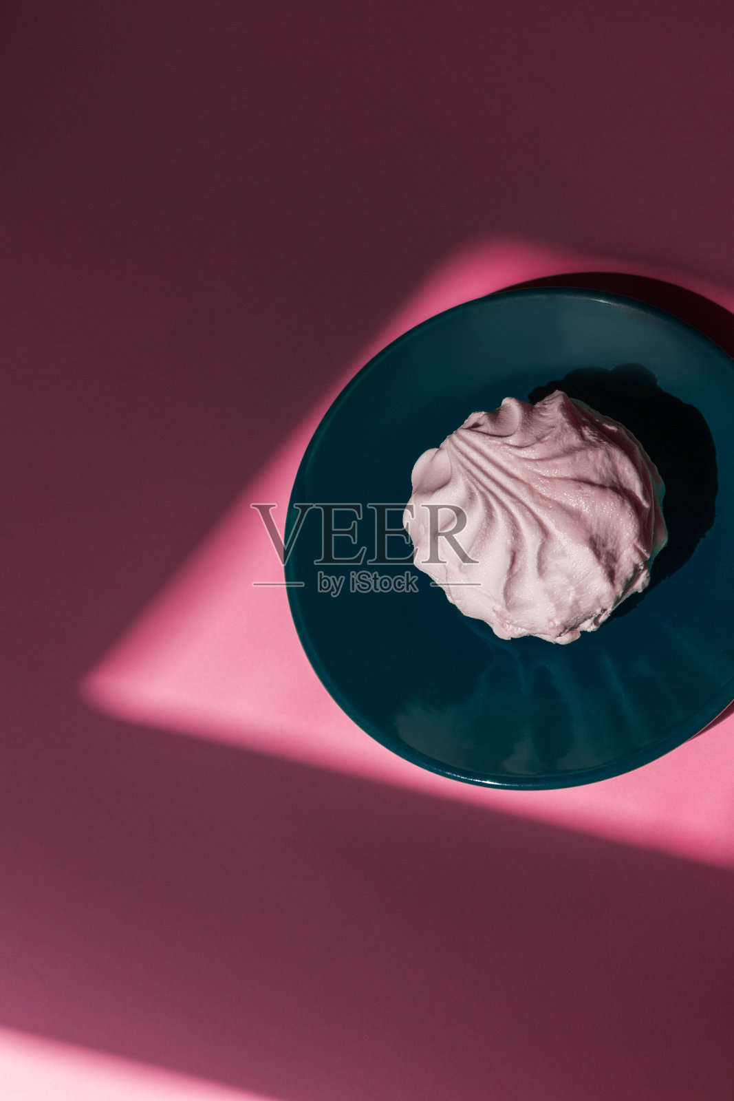 一个棉花糖放在粉红色背景的水绿色托盘上。照片摄影图片