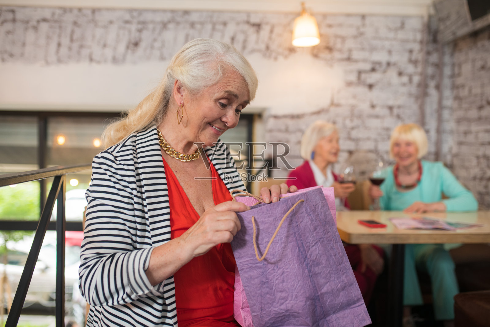 年长女性拿着购物袋，看上去很开心照片摄影图片