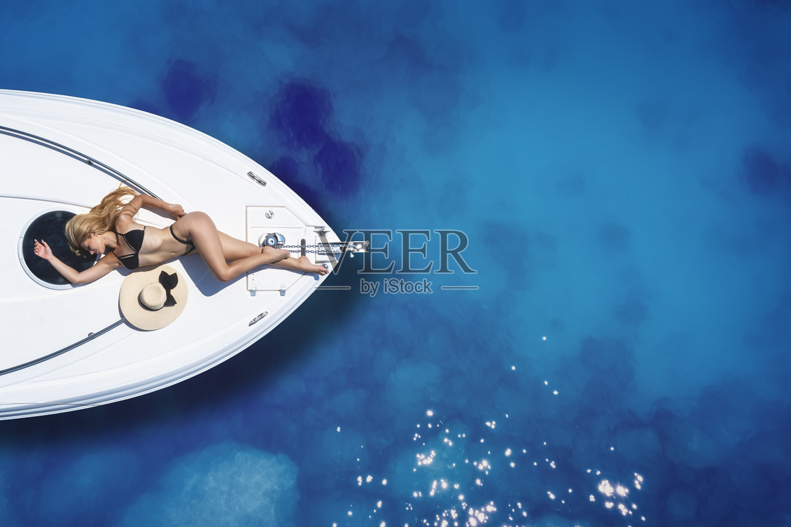 一个穿着比基尼的金发女人在船上晒日光浴照片摄影图片