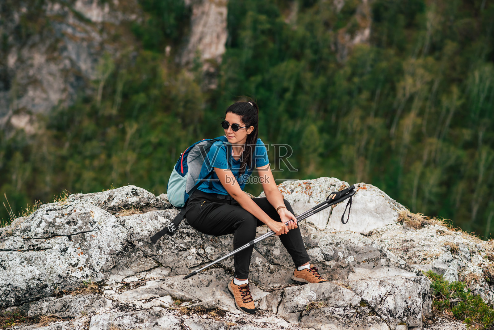 背着背包和登山杖的女人。背着登山杖和背包在山顶上的女徒步旅行者。用棍子走路的北欧人。一位女游客。徒步旅行。本空间照片摄影图片