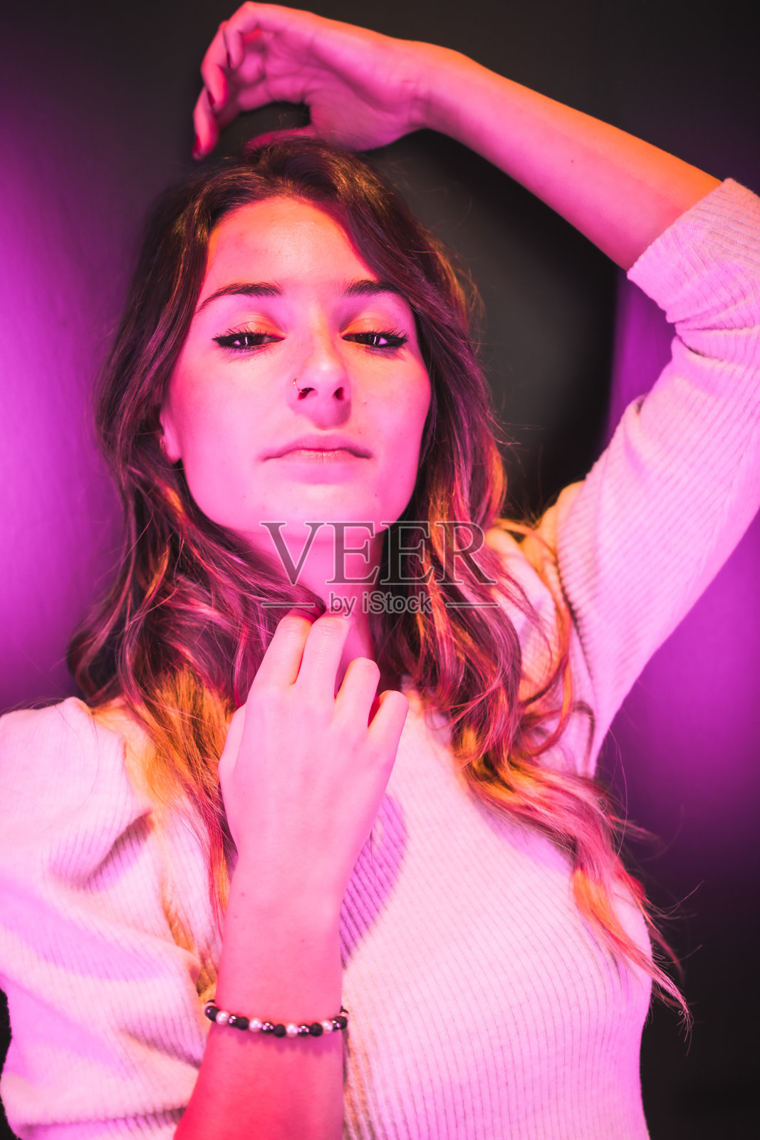 一个年轻女人的肖像看着相机与粉红色的led灯从一边照片摄影图片