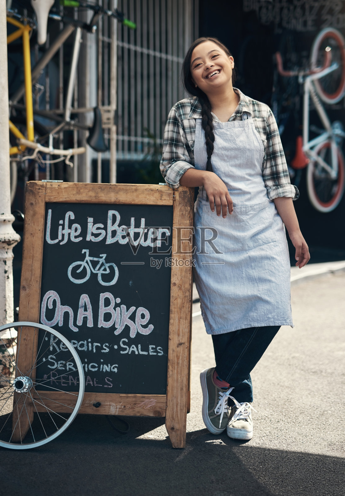 一个年轻女人的肖像靠在外面一个自行车修理店的招牌上照片摄影图片