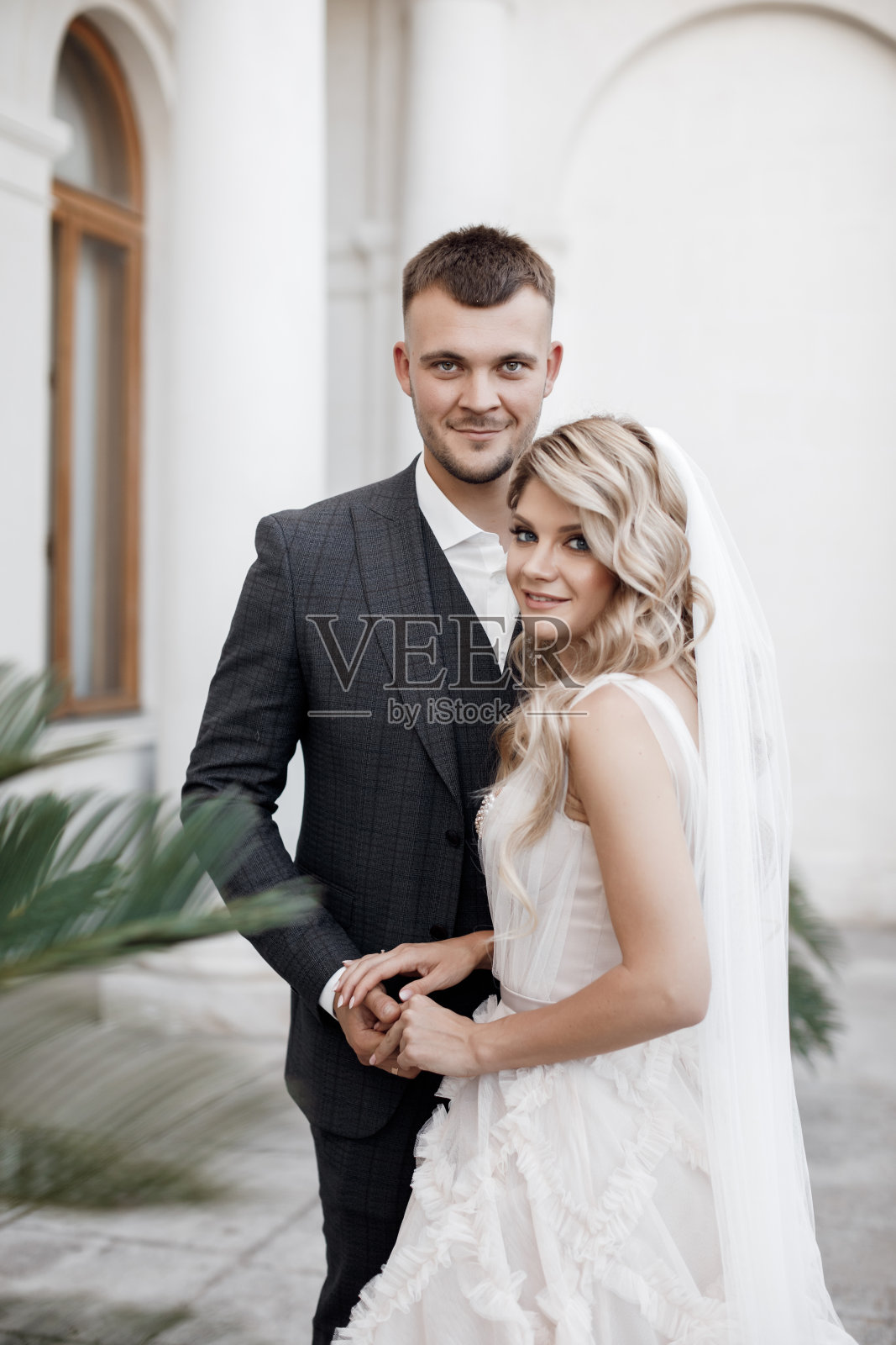 新娘身穿白色婚纱，新郎身穿深色西装，背景是婚礼宫殿照片摄影图片