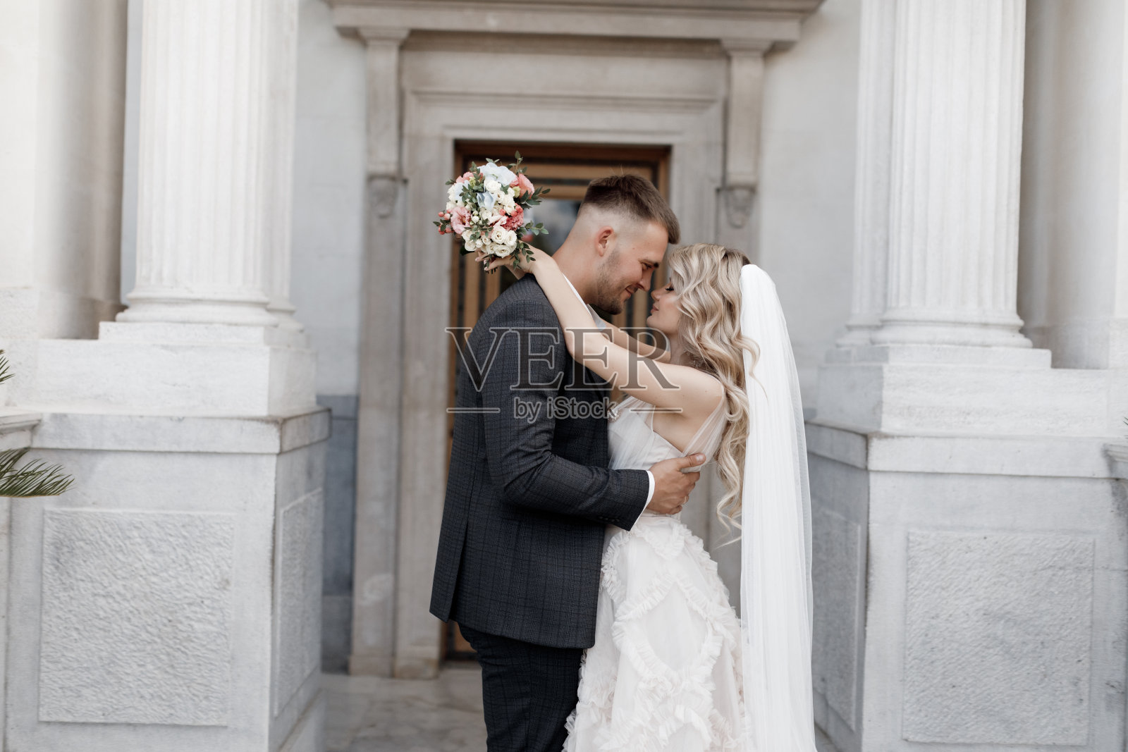 新娘身穿白色婚纱，新郎身穿深色西装，背景是婚礼宫殿照片摄影图片